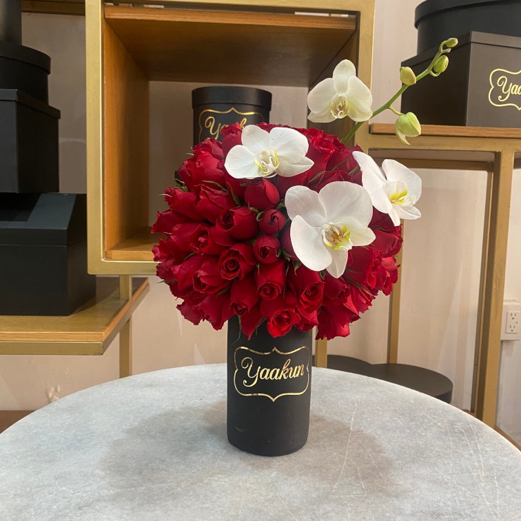 Jarron de barro negro con 120 rosas rojas y toques de orquidea blanca phalenosis
