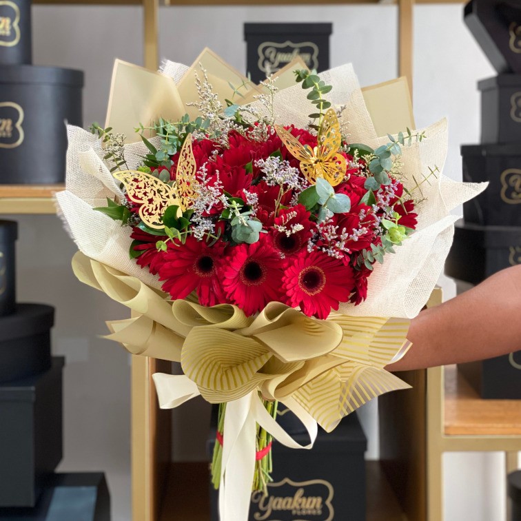 Ramo de 48 gerberas rojas con follajes y 2 mariposas en papel coreano